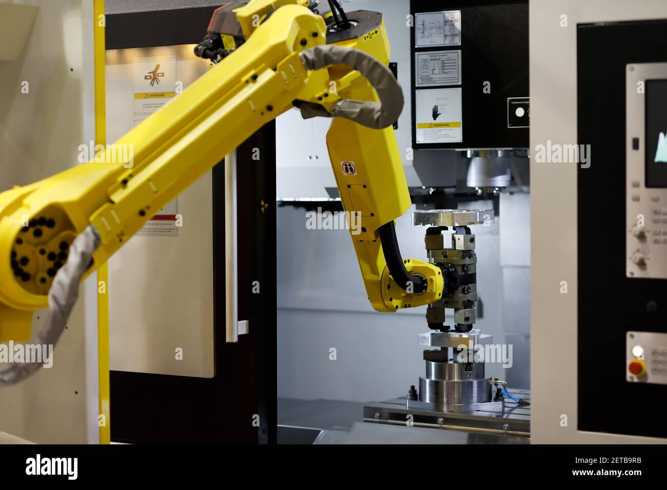 Roboterarm lädt ein Werkstück in die CNC-Maschine. Selektiver Fokus. Stockfoto