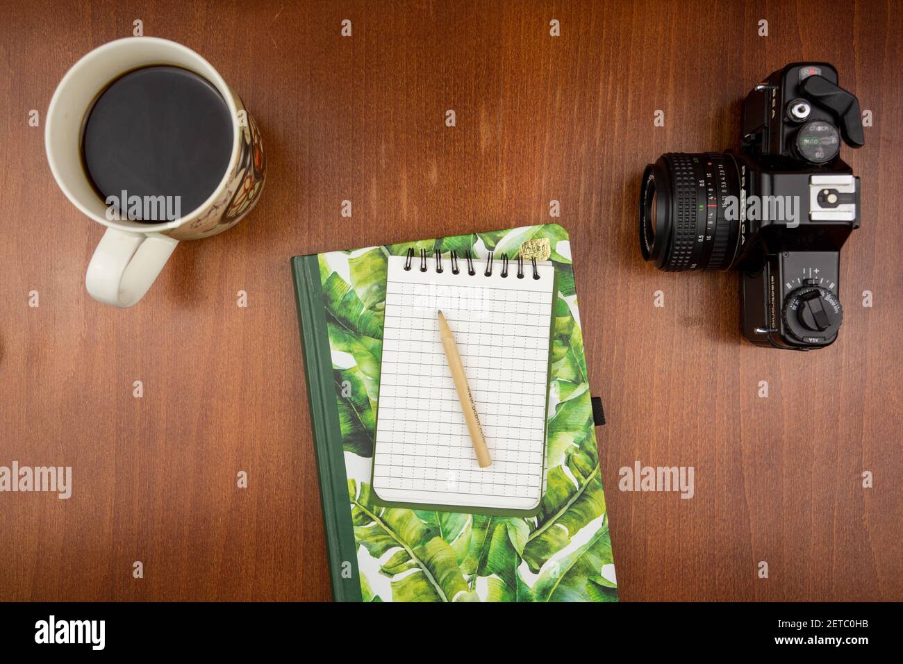 KATOWICE, POLEN - 12. Feb 2021: Draufsicht auf ein Notizbuch, das auf einem Holztisch neben einer Vintage-Kamera und Kaffee liegt Stockfoto