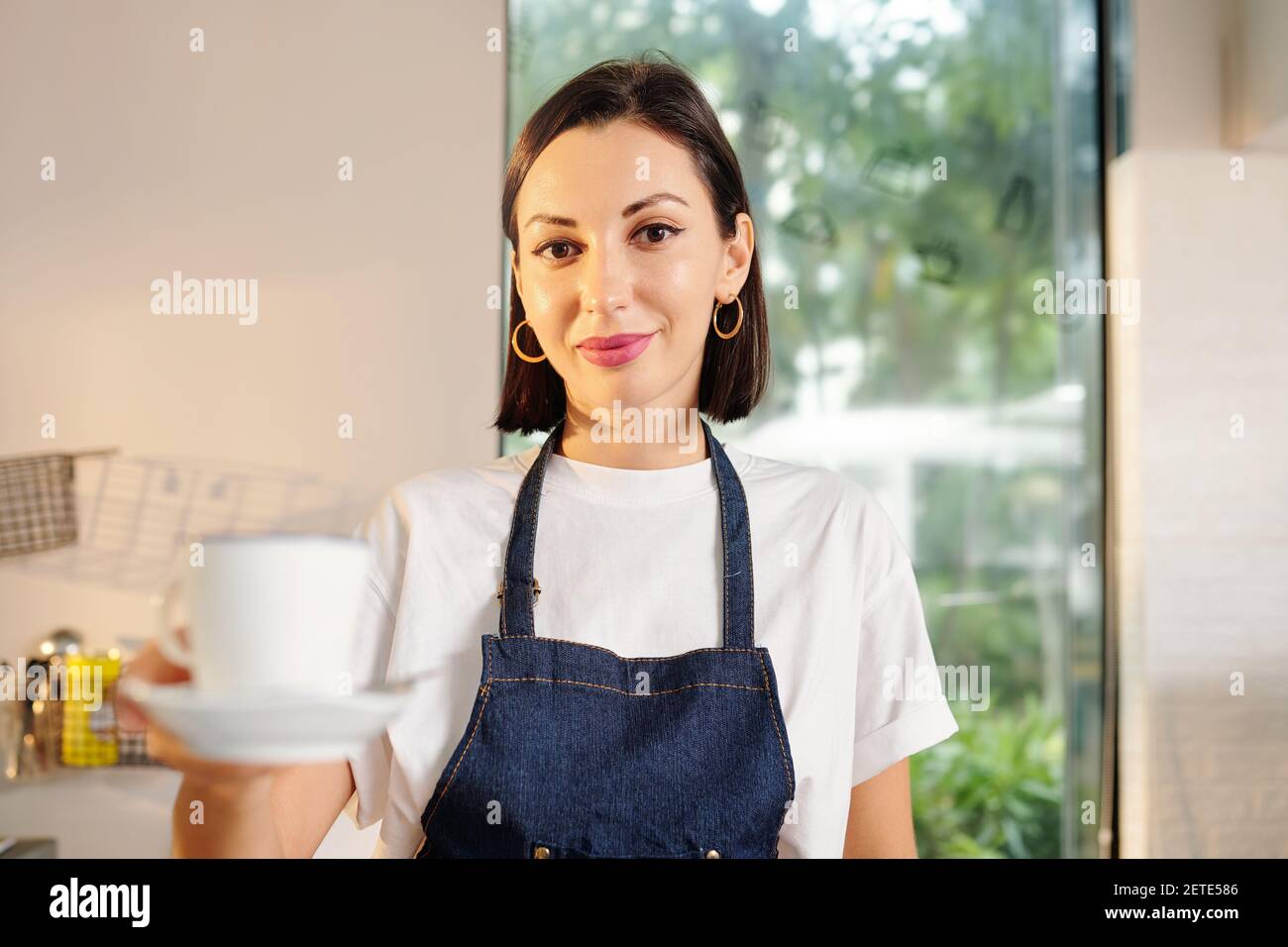 Kellnerin bietet eine Tasse Kaffee an Stockfoto