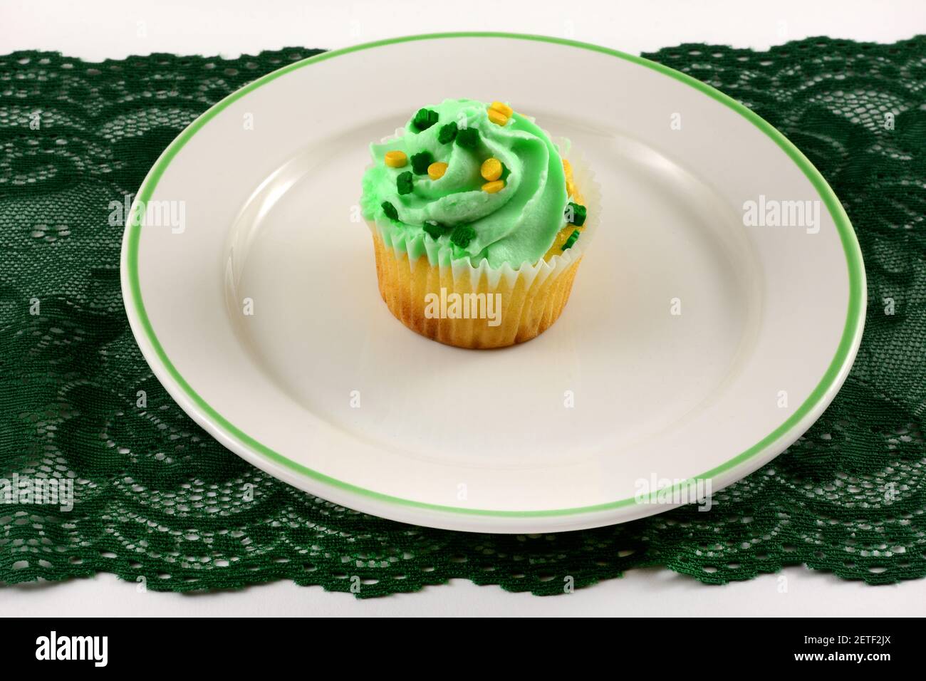 Saint Patrick's Day Brownie Cupcake mit weißem Glasur und Streuseln Auf weißem Dessert spät auf grüne Spitze in der Lage Läufer auf Weißer Tisch Stockfoto