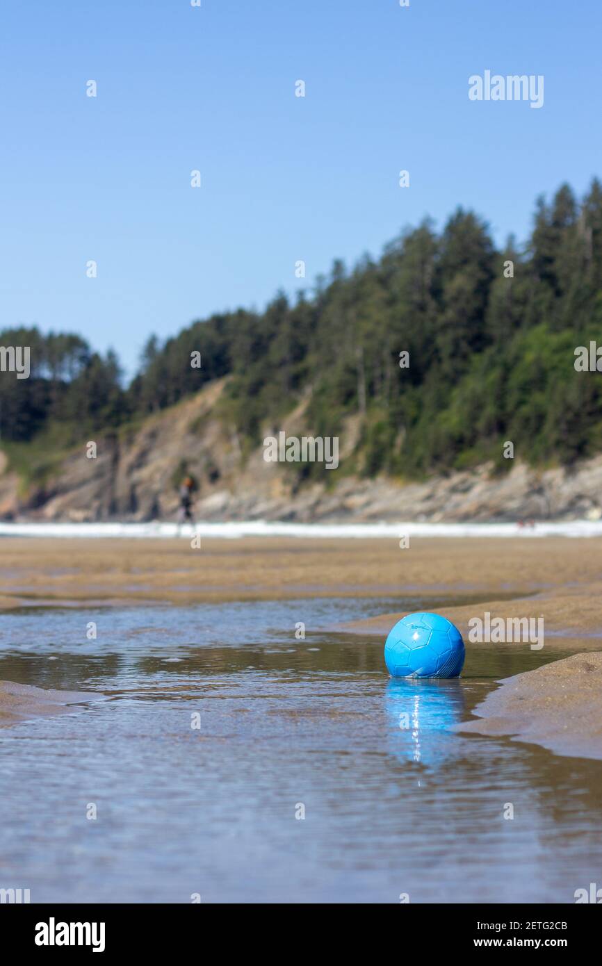 Blauer Fußball sitzt in einem der Pools von Das Delta eines Baches, der sich in die Smuggler Cove entleeren Short Sand Beach an der Küste von Oregon Stockfoto