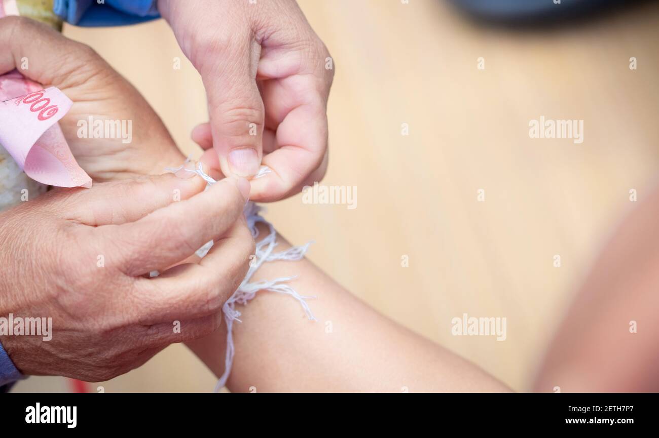 Die Zeremonie der Bindung von Menschen Handgelenk mit dem heiligen Faden zu trösten Menschen Kwan. Thailändische Kultur. Glaubensrichtungen und lokale Kultur des nordöstlichen Thailands. Stockfoto