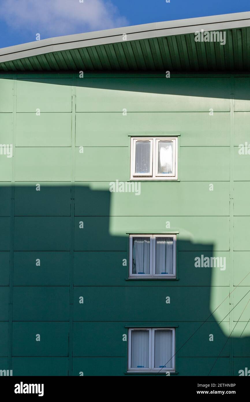 Wohnblock mit drei Fenstern und einem starken Schattenschuss in grafischer Weise. Stockfoto
