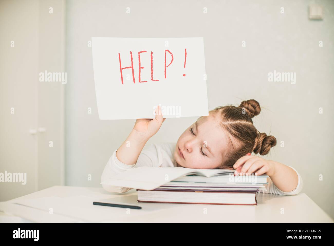 Traurig müde frustriert Mädchen sitzt am Tisch mit vielen Büchern und Papier mit Wort Hilfe. Lernschwierigkeiten. Hochwertige Fotos Stockfoto