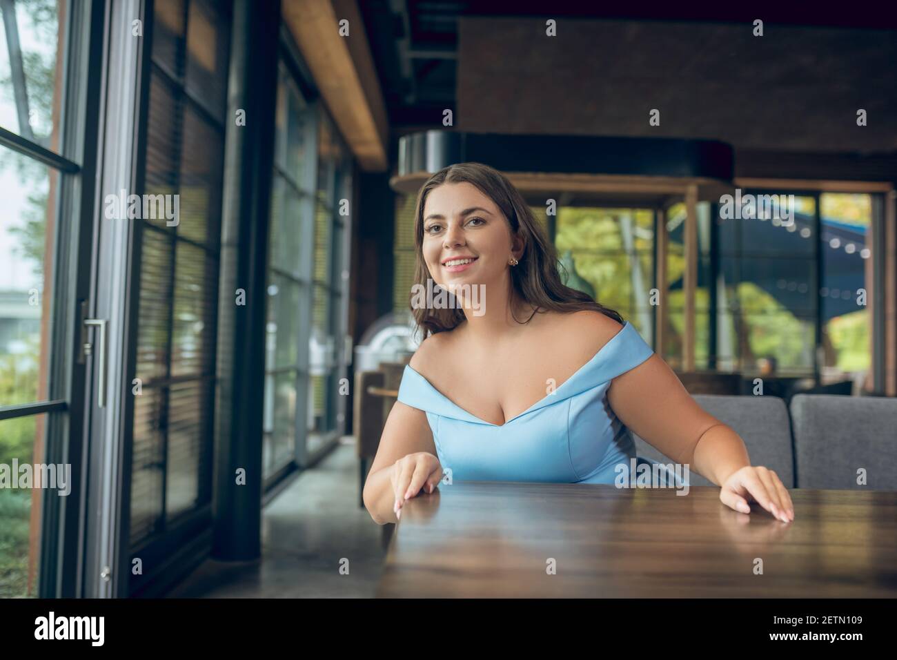 Freudige Frau wartet auf Treffen im Café Stockfoto