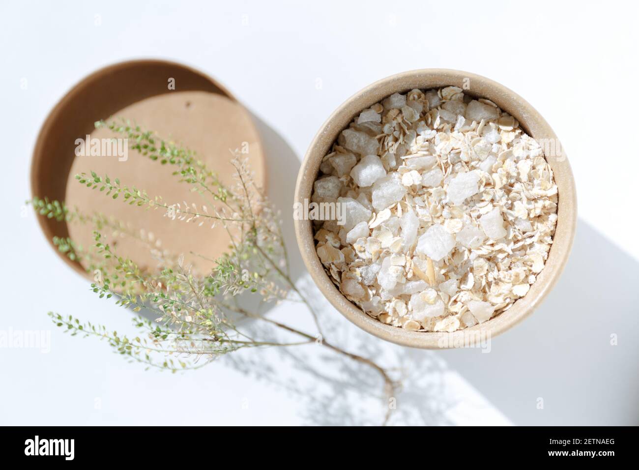 Pappbecher mit Haferflocken und grobem Meersalz aus nächster Nähe. Schrubben Sie die Haut. Spa-Produkte zur Hautreinigung und Entspannungsbad auf weißem Hintergrund mit Stockfoto