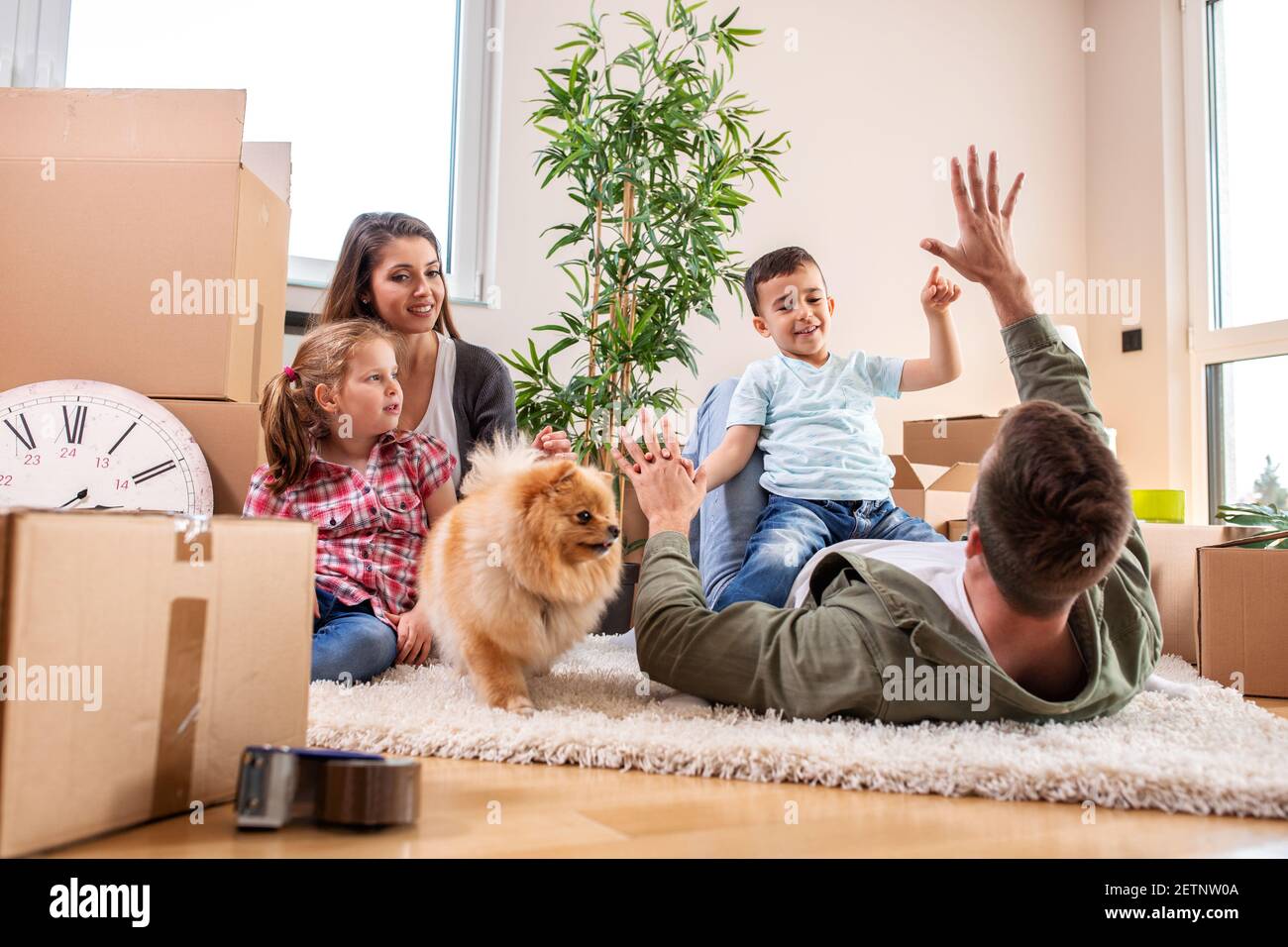Mama, Papa, ihre Kinder und ihr Hund ziehen in die neue Wohnung und haben Spaß dabei Stockfoto