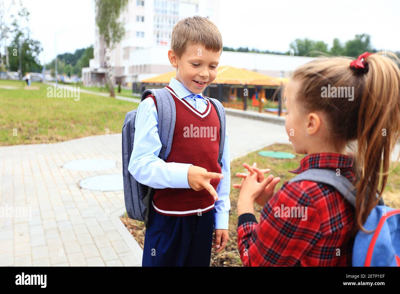 Kinder mit Aktentaschen über den Schultern auf dem Hintergrund der Schule. Stockfoto