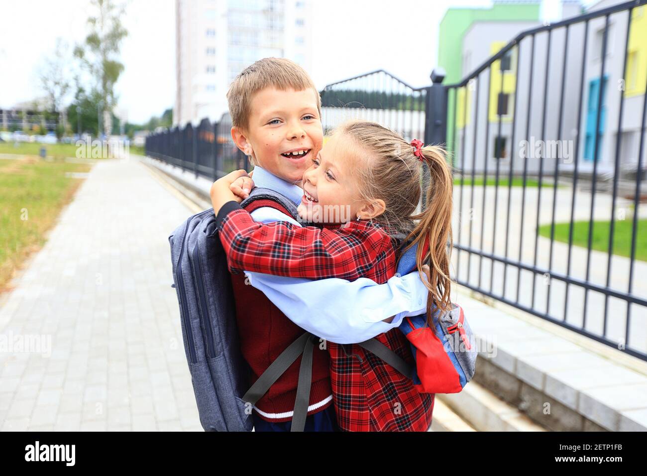 Kinder mit Aktentaschen über den Schultern auf dem Hintergrund der Schule. Stockfoto