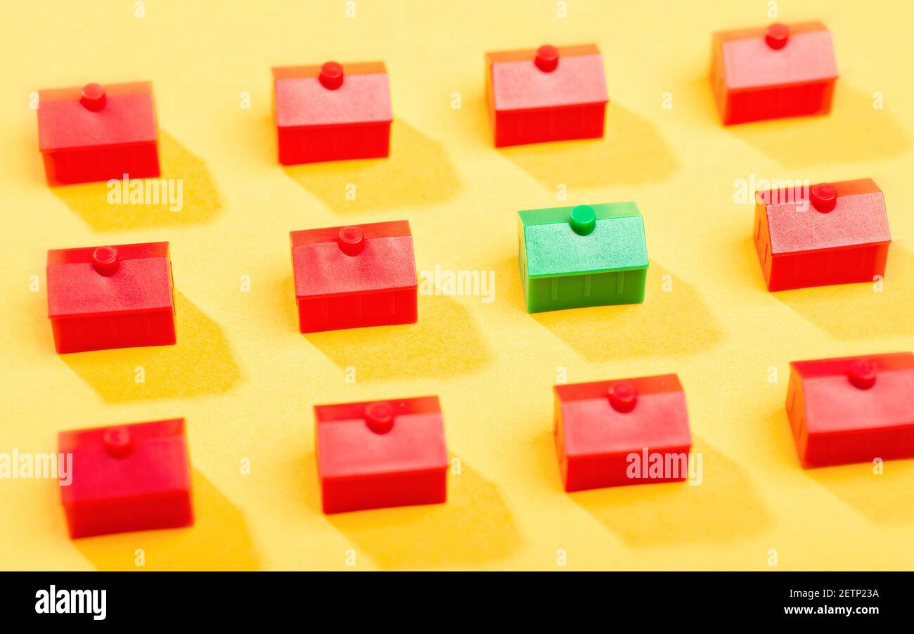Ein kleines grünes Haus steht inmitten von vielen Rote Häuser Stockfoto