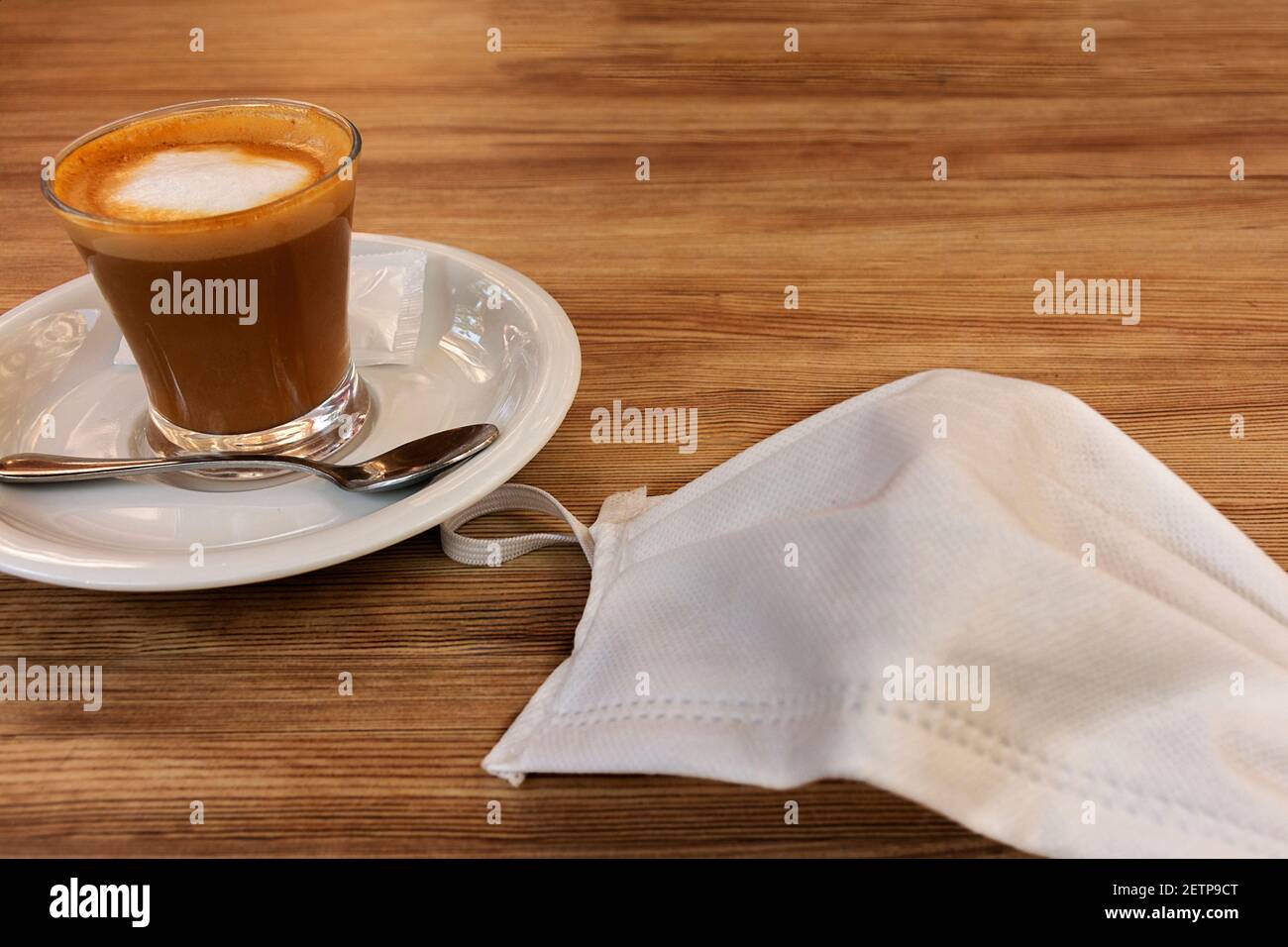 Espresso Macchiato und Anti-Virus Gesichtsmaske auf dem Tisch einer Bar Terrasse. Konzepte von Coronavirus, Pandemie, Unsicherheit oder Unconfined Stockfoto