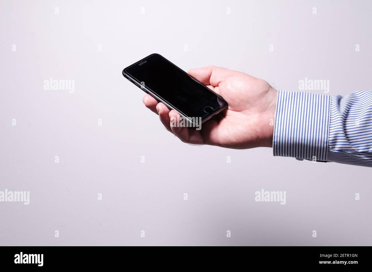 Männliche Hand hält iPhone Smartphone oder Handy mit leerem Display vor weißem Hintergrund, Kommunikationskonzept, innen, Studio Stockfoto
