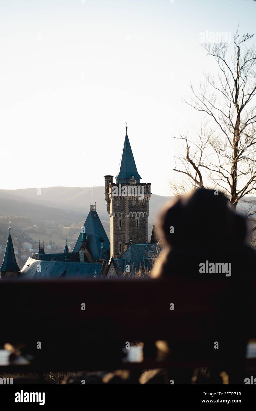 Nahaufnahme Aufnahme bei Sonnenuntergang auf Schloss Wernigerode in Deutschland. Junge Frau sitzt auf der Bank und schaut zum castl Stockfoto