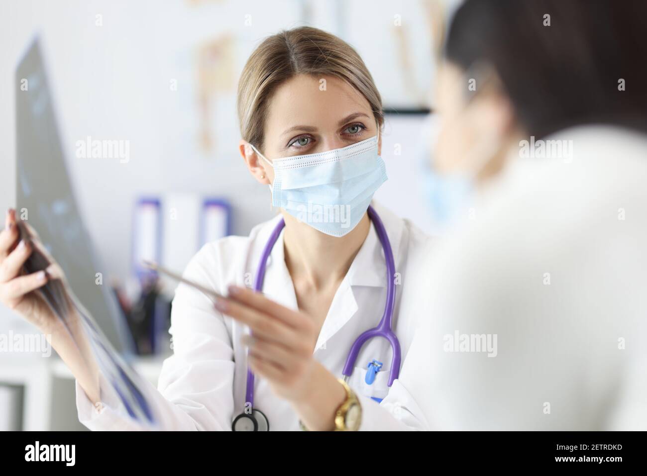 Arzt in Schutzmaske mit Röntgenaufnahme des Patienten Stockfoto
