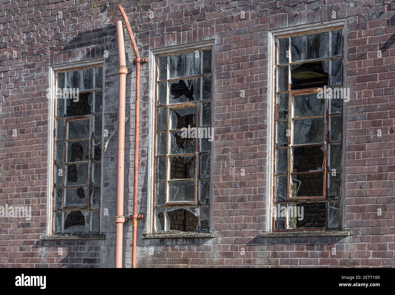 Eine Nahaufnahme von drei kaputten alten Fenstern auf einem verlassenen Gebäude. Alle Glasscheiben sind gebrochen Stockfoto