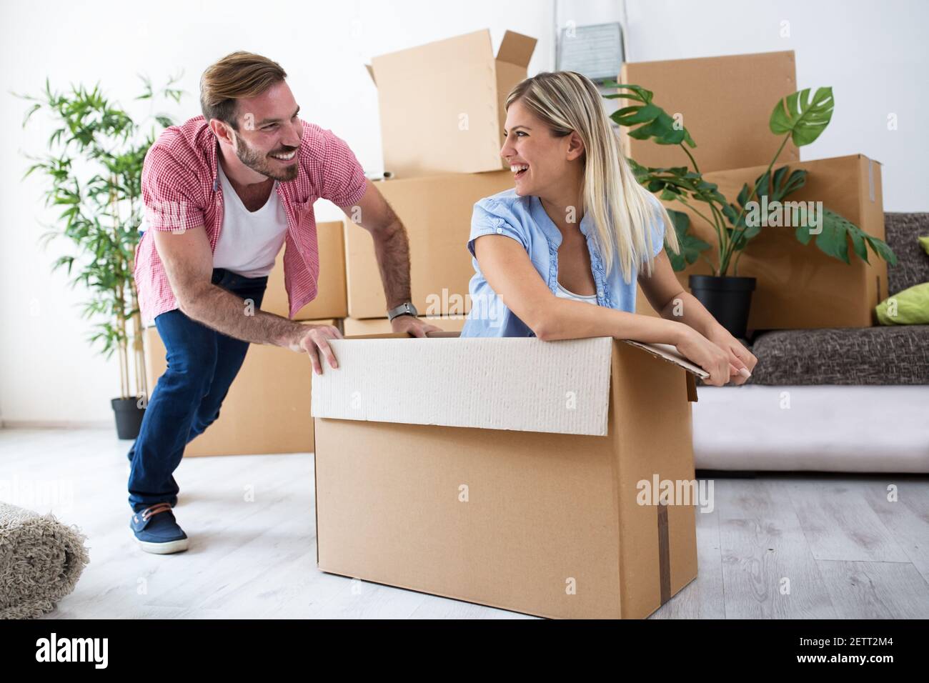 Happy Young Pärchen Feier Kauf neue Wohnung, Spaß haben und fahren mit Box  durch Zimmer Stockfotografie - Alamy