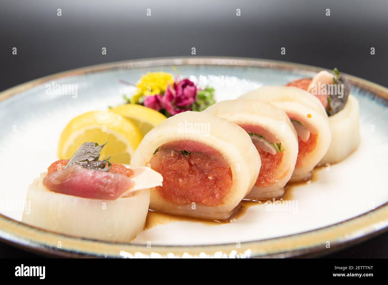 Ringe von Albacore-Fisch gefüllt mit würzigen Thunfisch Sushi mit schöner Präsentation auf einem Teller garniert mit einer Blume gekrönt. Stockfoto