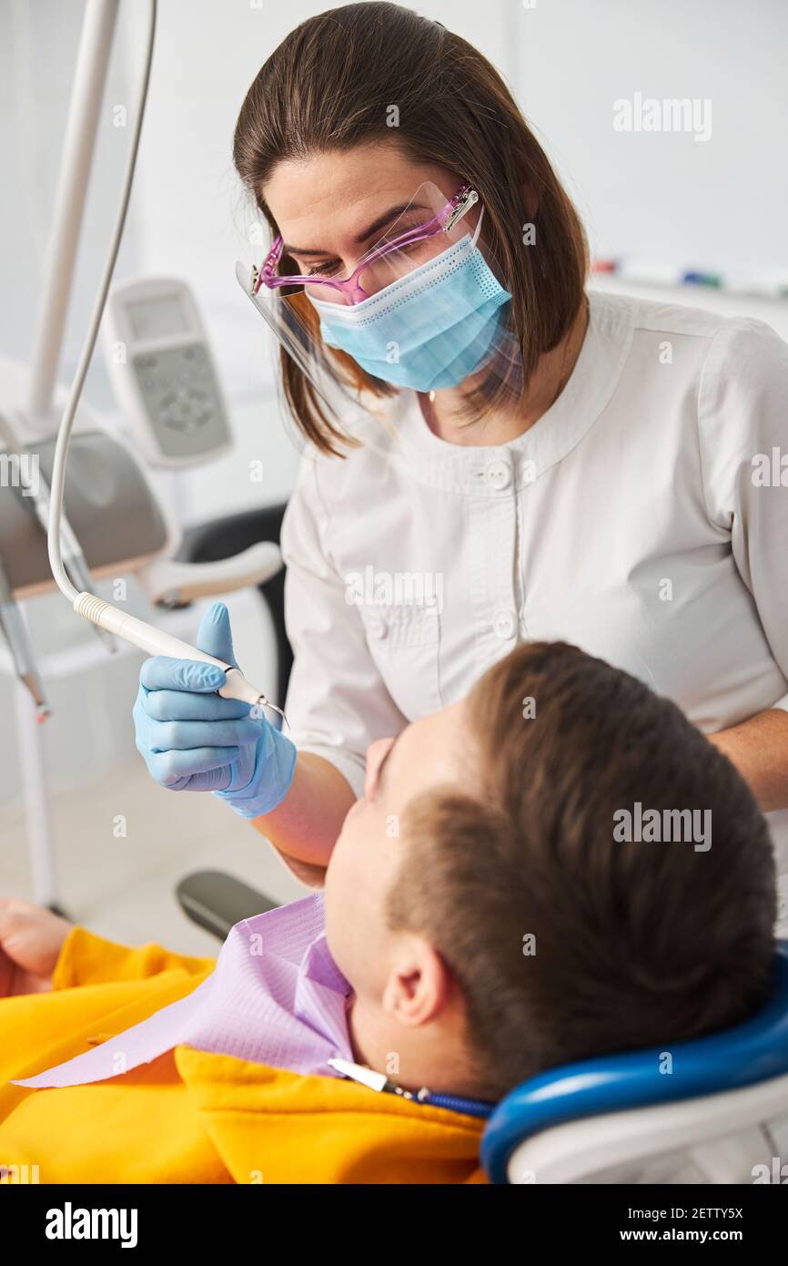 Weibliche Zahnärztin mit Zahnscaler auf einen Mann Stockfoto