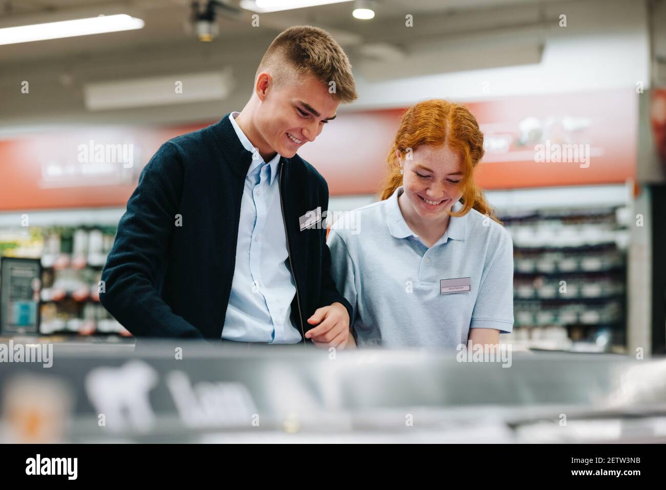 Junger Mann und Frau im Supermarkt. Auszubildende arbeiten zusammen im Lebensmittelgeschäft. Stockfoto