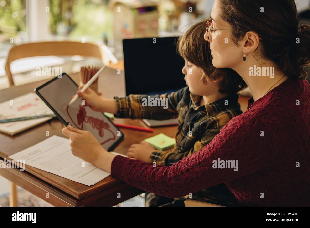 Mutter und Sohn mit Stylus-Stift und machen Zeichnung auf digitalen Tablet zu Hause. Frau lehrt, wie man auf Grafik-Tablet zu ihrem Sohn zeichnen. Stockfoto
