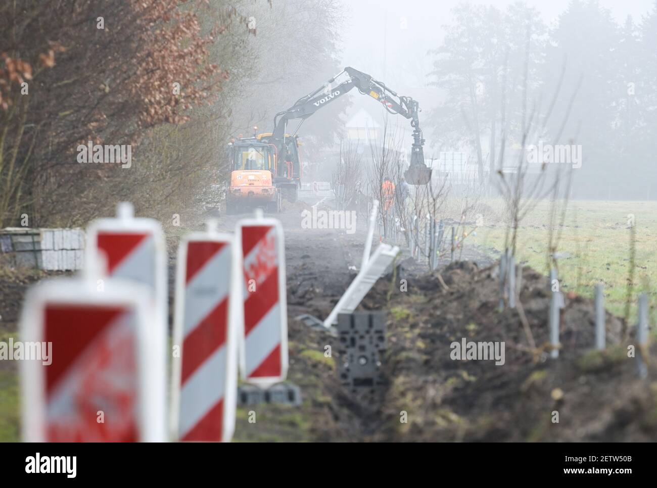 Beelitz, Deutschland. März 2021, 02nd. Arbeiter legen Rohre am Rande des Geländes der zukünftigen State Garden Show (LAGA). Auf der rechten Seite des Weges pflanzten Eltern 2018 Obstbäume für ihre Kinder. Am Nachmittag wird Brandenburgs Landwirtschaftsminister Vogel über den Stand der Vorbereitungen für die Landesgartenschau berichten. Quelle: Soeren Stache/dpa-Zentralbild/ZB/dpa/Alamy Live News Stockfoto