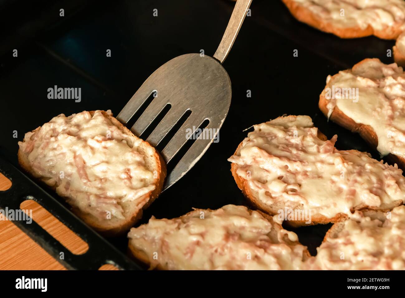 Gebackene Sandwiches mit Käse und Schinken auf dem Backblech. Heißer ...