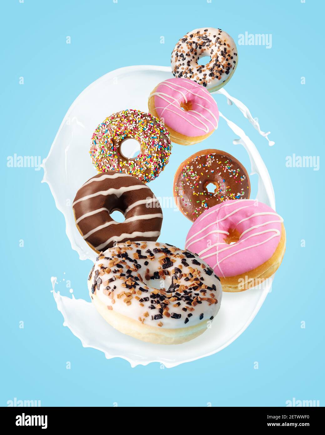 Verschiedene frische Donuts mit Milchspritzern auf blauem Hintergrund. Minimales Lebensmittelkonzept. Stockfoto