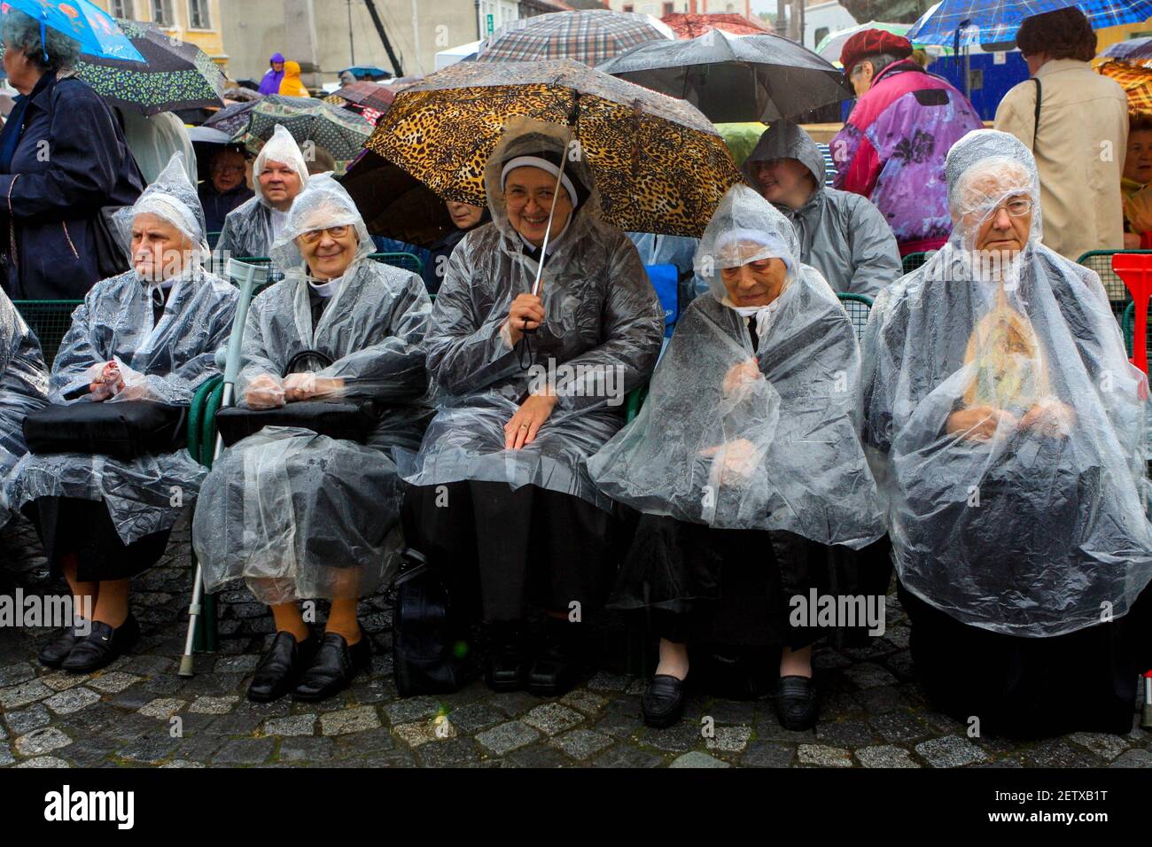 Katholische Nonnen an einem regnerischen Tag, Plastikregenmäntel, Regenschirm, Seniorinnen ältere Generation Stockfoto