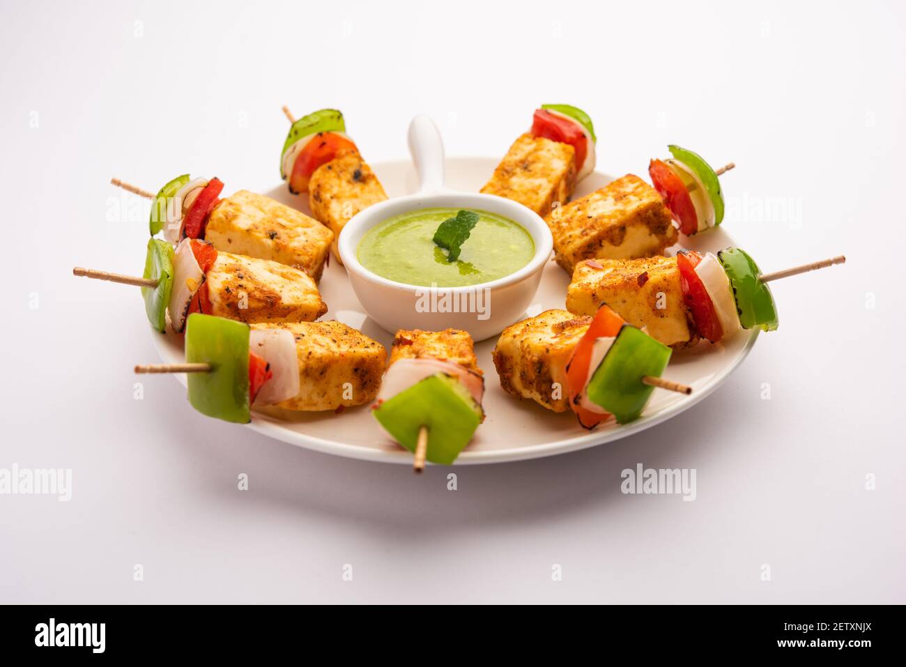 Starter-Snack Paneer Tikka mit Stick in Teller mit grünen Chutney isoliert auf weißem Hintergrund. Indische Küche Gericht mit gegrilltem Hüttenkäse mit Stockfoto