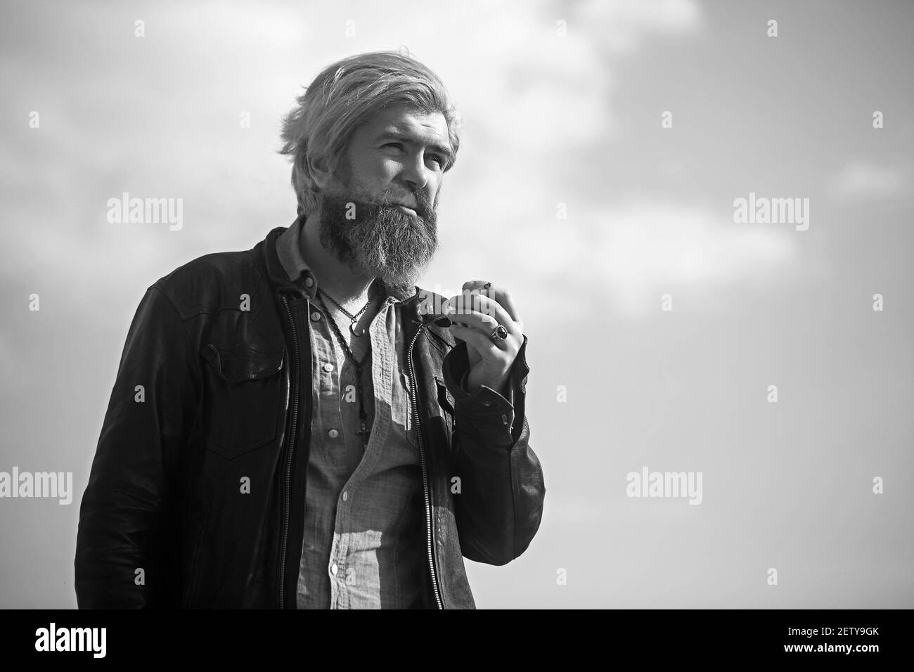 Bärtiger Hipster auf der Spitze des hohen Gebäudes mit Stadtbild im Hintergrund. Stockfoto