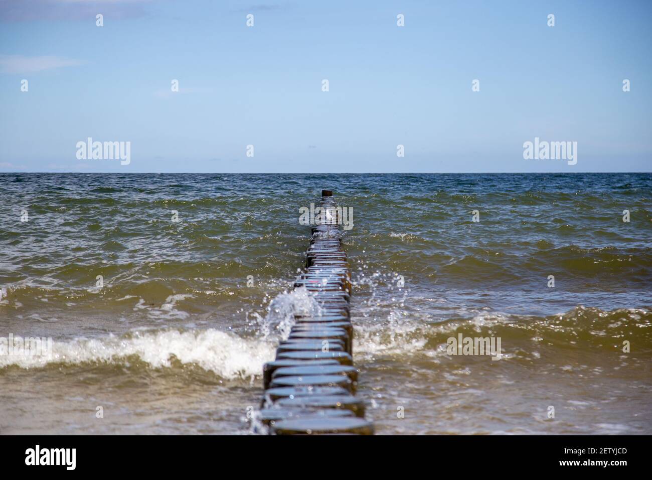 Im Sommer brechen die Wellen auf den Holzplanken an der Ostsee. Stockfoto