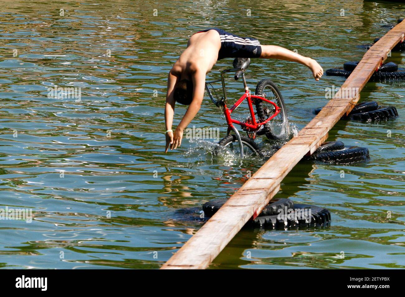 Ungewöhnliche Sportarten, ein Mann überquert das Wasserreservoir mit dem Fahrrad, Fall off, Tschechien im Sommer ländliche Leben, ein jährliches Wettkampf-Wasserrad Stockfoto