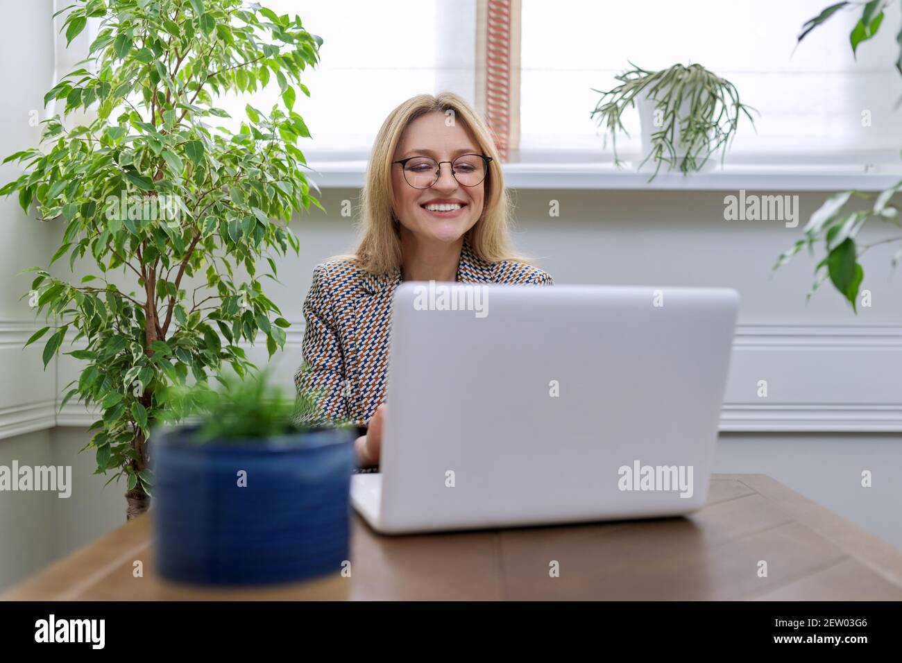 Reife, selbstbewusste Geschäftsfrau, die mit einem Laptop zuhause aus der Ferne arbeitet Stockfoto