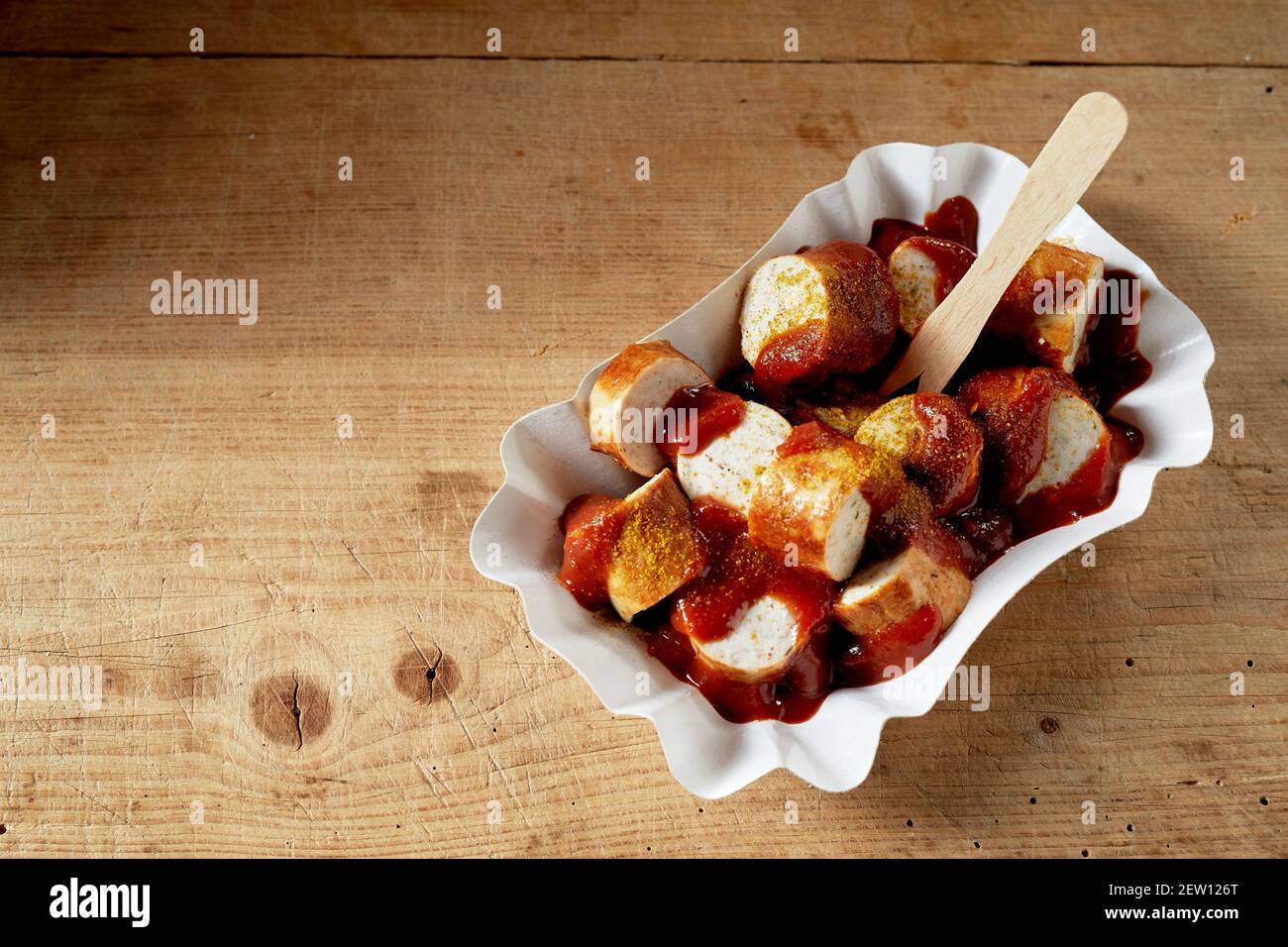Hoher Winkel von appetitlich weichen Schweinefleisch Wurst Scheiben bedeckt mit Tomatensauce und trockenes Curry im Einwegbehälter Stockfoto