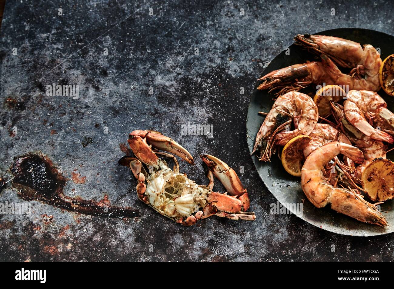Blick von oben auf appetitlich gegrillte Krabben mit Krallen in der Nähe des Tellers Mit verschiedenen ganzen Garnelen und Zitronenscheiben Stockfoto