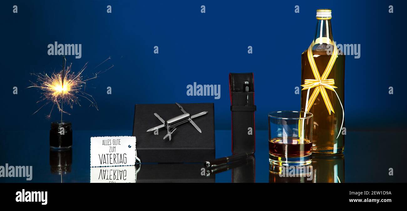 Edle Geschenkideen für den Vatertag. Festlich fotografiert mit Glanz und Reflexion. Eine kleine Karte enthält deutschen Text: Happy Father's Day. Stockfoto