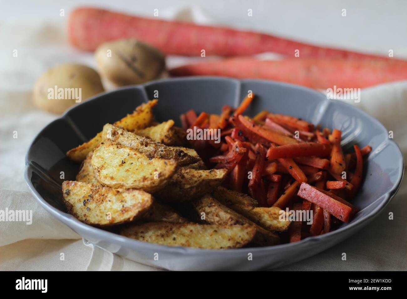 Sautierte Karotten und luftgebratene Kartoffelkeile. Der einfachste und gesunde Weg, um Karotten. Aufnahme auf weißem Hintergrund Stockfoto