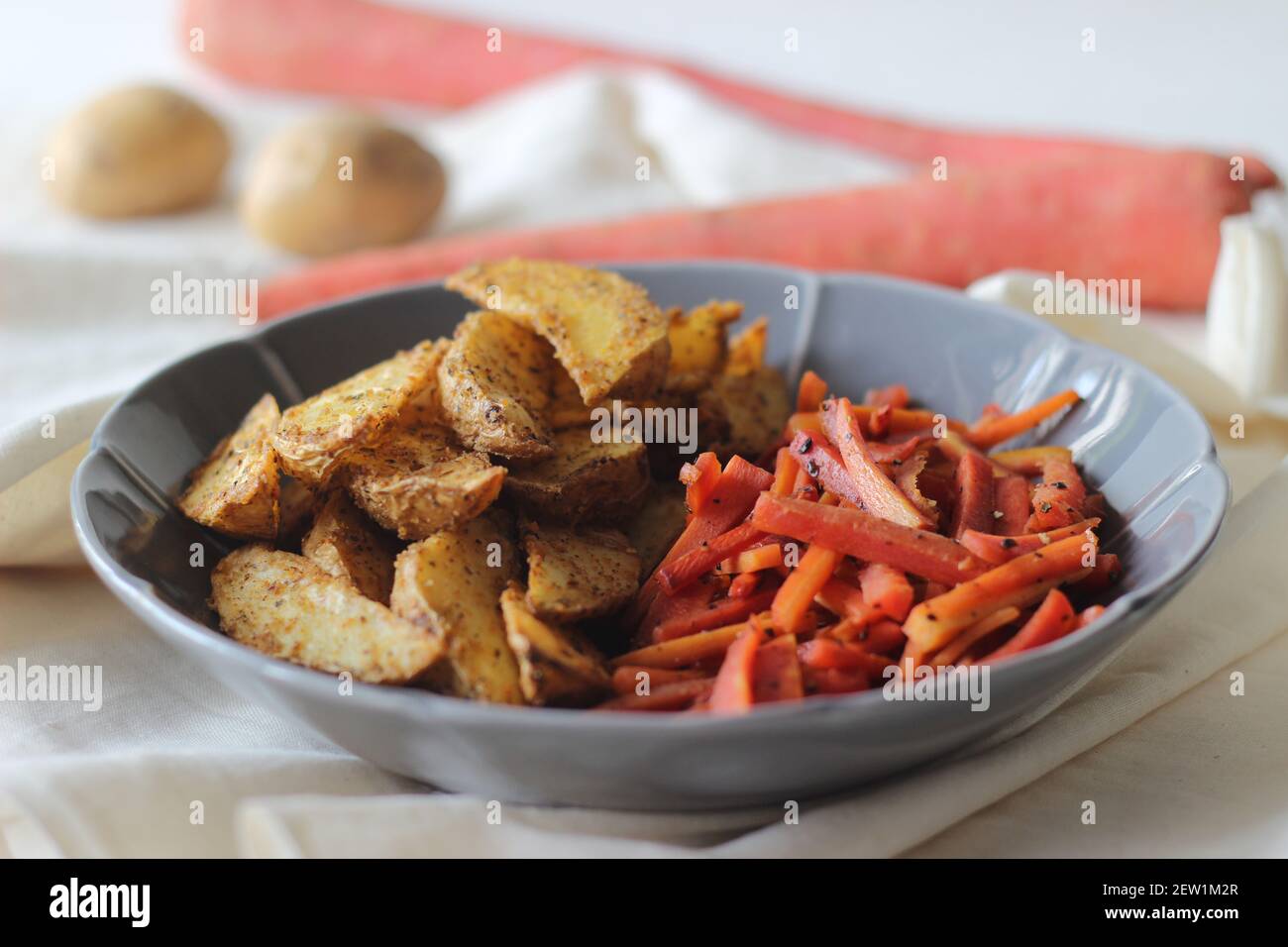 Sautierte Karotten und luftgebratene Kartoffelkeile. Der einfachste und gesunde Weg, um Karotten. Aufnahme auf weißem Hintergrund Stockfoto