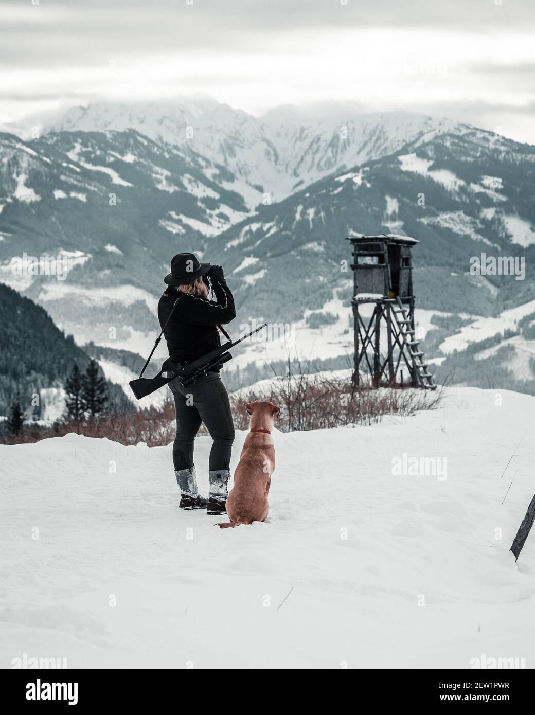 Jagdmädchen mit Hund in einer Winterlandschaft in den österreichischen Bergen. Stockfoto