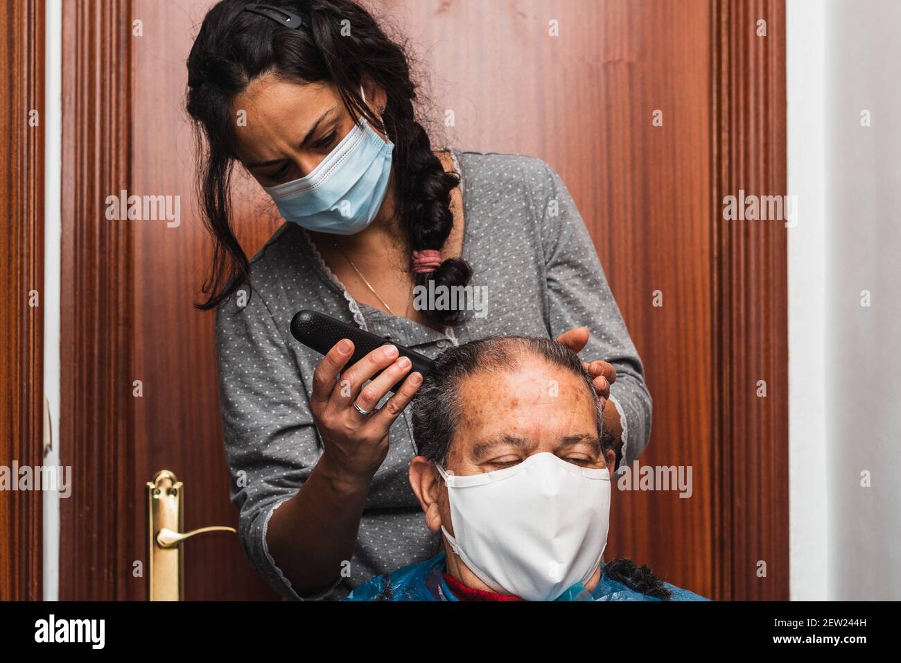 Tochter schneidet ihrem Vater die Haare zu Hause, horizontal Stockfoto