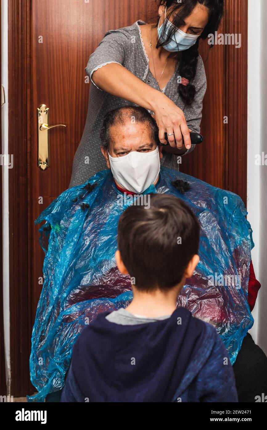 Tochter schneidet ihrem Vater die Haare zu Hause, vertikal Stockfoto