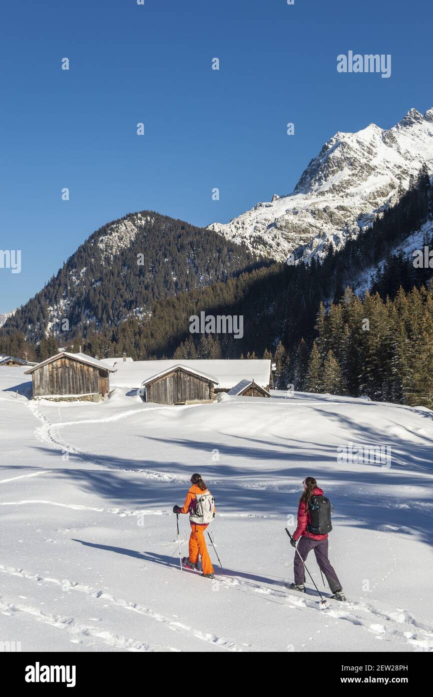 Frankreich, Haute Savoie, Mont Blanc Massiv, Les Contamines Montjoie, zwei junge Frauen wandern mit Schneeschuhen im Rollaz Tal in Richtung der Chalets de la Rollaz im Naturschutzgebiet, und die Tete Noire und die Grande Roche de Tre la Tete Stockfoto