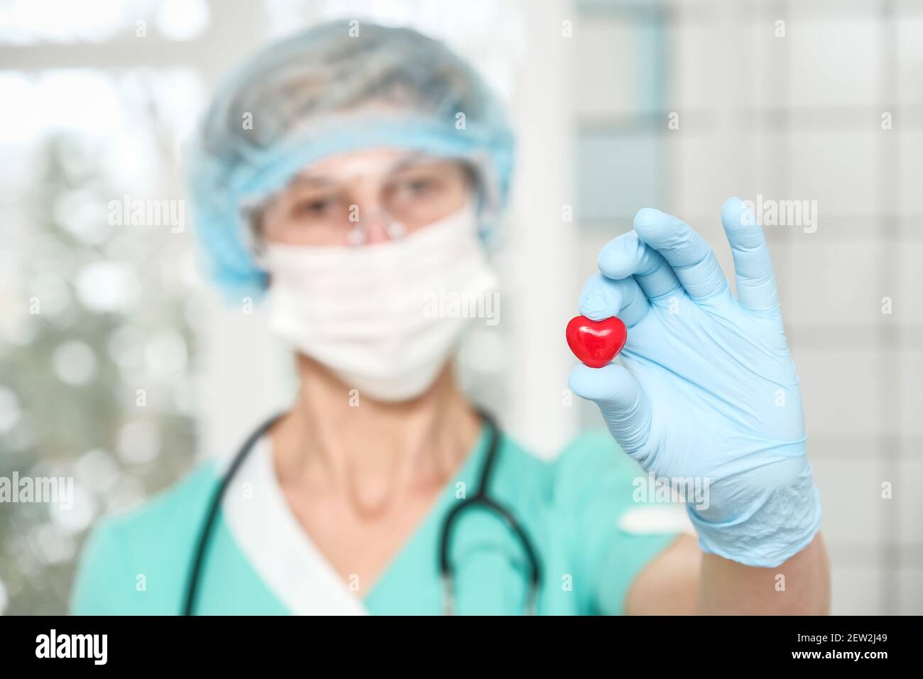 Kardiologe hält rotes Herz im Schutzhandschuh Stockfoto