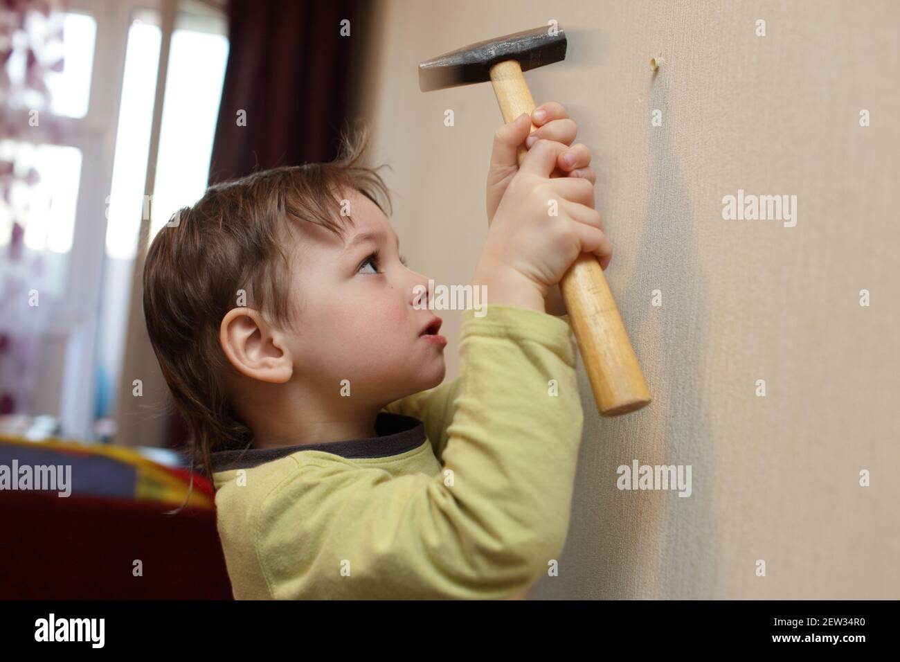 Kind hämmert Plastikanker in die Wand zu Hause Stockfoto