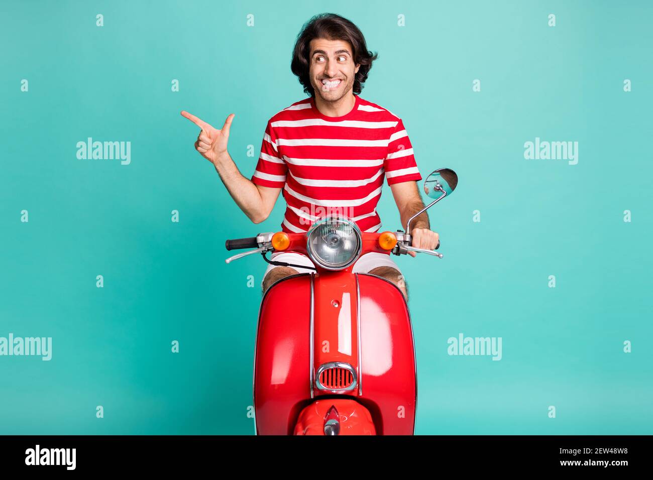 Portrait von schönen fröhlichen Kerl Reiten Moped zeigt Kopie leer Leerer Raum isoliert über hellgrünen türkisfarbenen Hintergrund Stockfoto