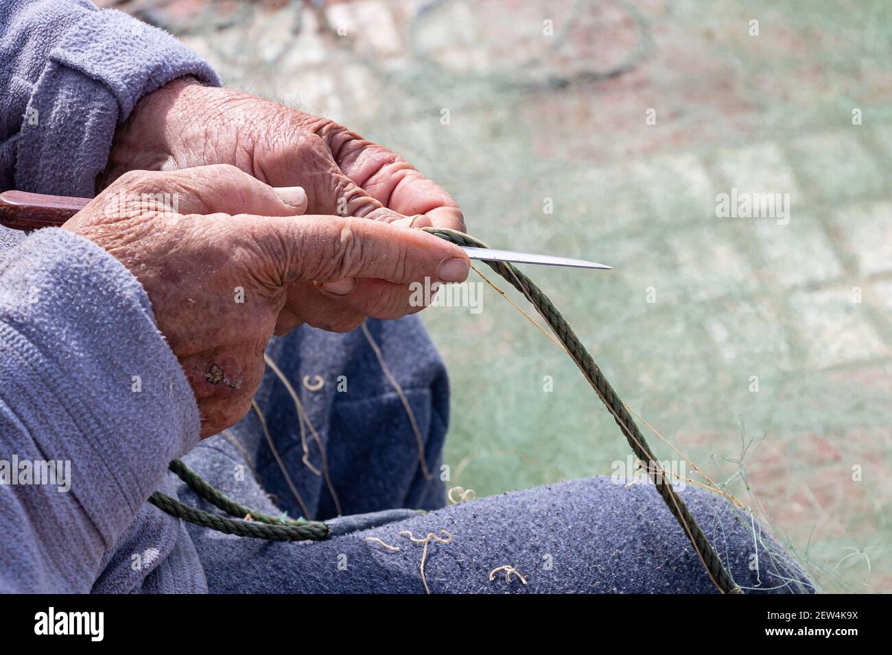 Hände des Fischers, die ein Netz mit einem Messer reparieren Stockfoto