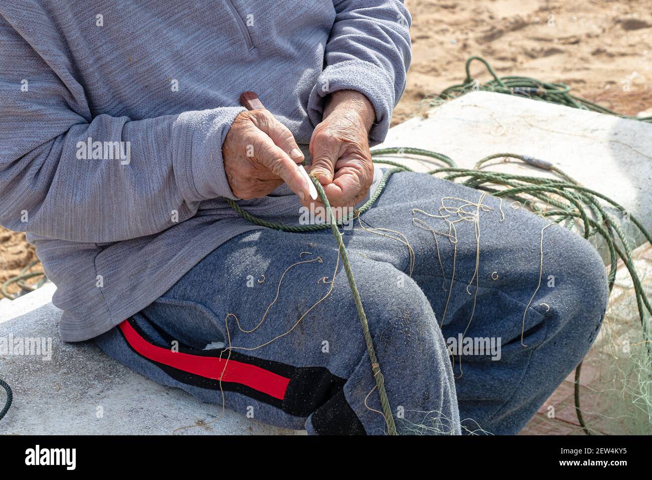 Hände des Fischers, die ein Netz mit einem Messer reparieren Stockfoto