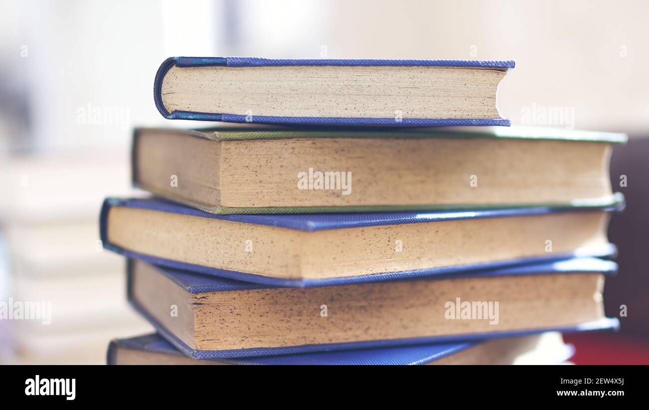 Mehrere alte und leicht abgenutzte Bücher in einem Turm gestapelt Auf einem Schreibtisch Stockfoto