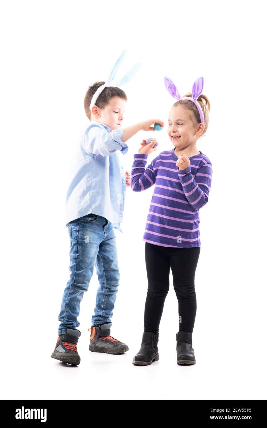 Spielerische junge Geschwister Kinder spielen Osterei knacken Kampf. Ganzkörper isoliert auf weißem Hintergrund. Stockfoto