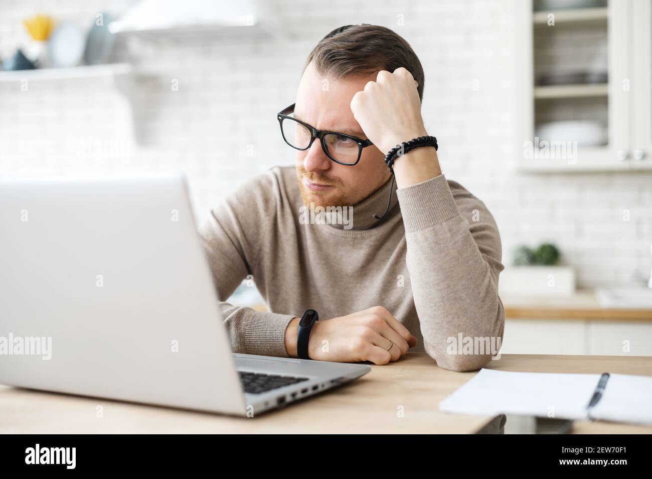 Business-Mann sitzen am Tisch in der Küche in der Nähe von Laptop, ruhen Kopf auf der Hand, denkt über Strategie, Arbeit entfernt von zu Hause, kreative Arbeit, Generierung neuer frischer Ideen, Suche nach Lösung. Zweifel Konzept Stockfoto